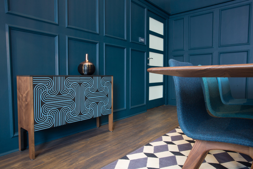 Immagine di una sala da pranzo minimalista chiusa con pareti blu, parquet scuro, camino classico e cornice del camino in intonaco