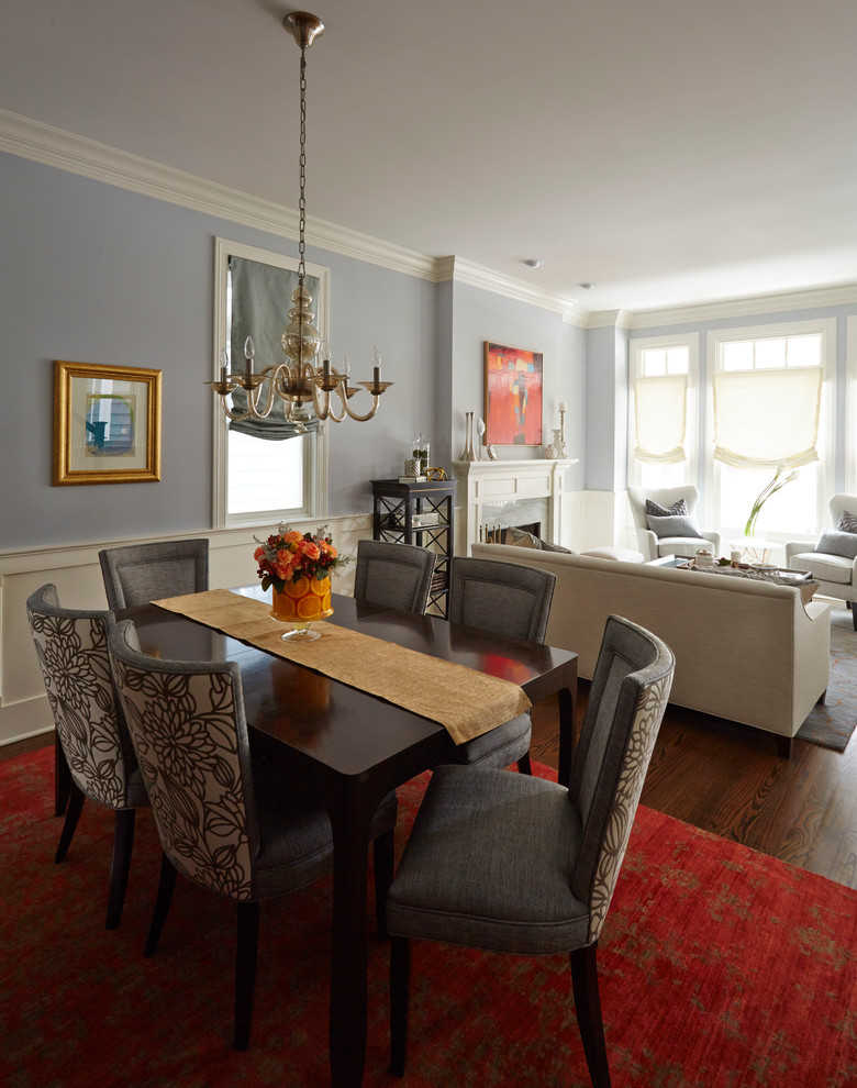 Cette image montre une salle à manger ouverte sur le salon traditionnelle de taille moyenne avec un mur bleu, parquet foncé, une cheminée standard et un manteau de cheminée en pierre.