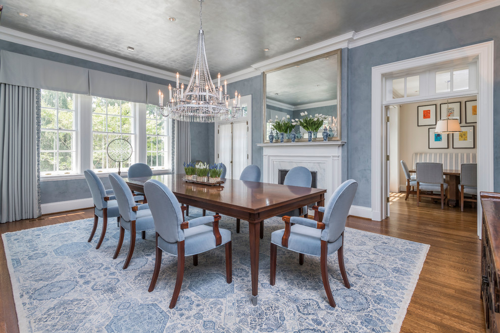Стильный дизайн: столовая в классическом стиле с синими стенами, темным паркетным полом, стандартным камином и коричневым полом - последний тренд