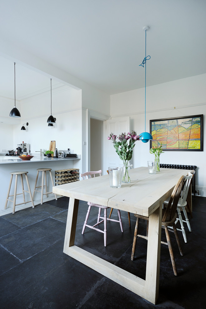 Immagine di una sala da pranzo aperta verso la cucina nordica con pareti bianche e pavimento grigio