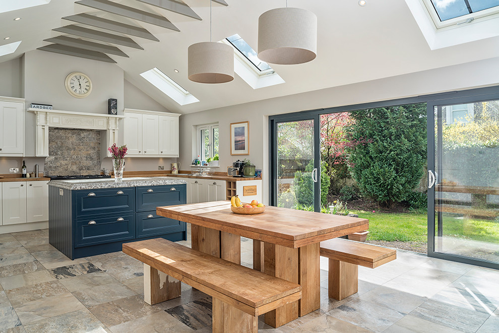 Immagine di una grande sala da pranzo aperta verso la cucina country con pareti grigie e pavimento beige