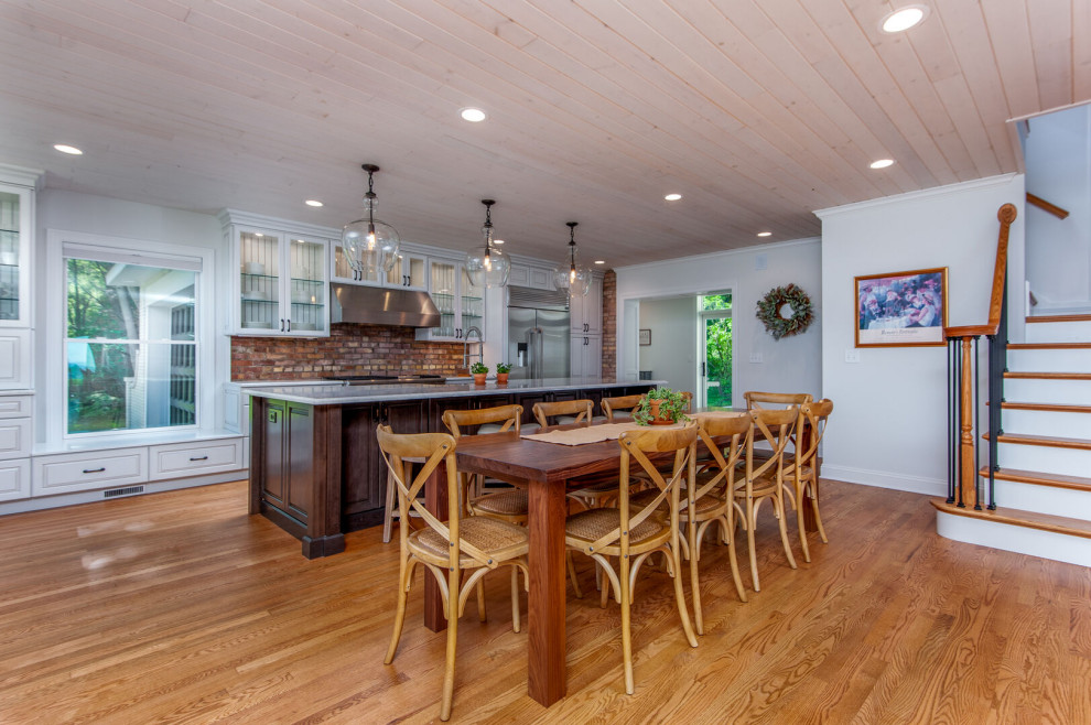 Foto di una sala da pranzo aperta verso la cucina country di medie dimensioni con pareti grigie, pavimento in legno massello medio e pavimento marrone