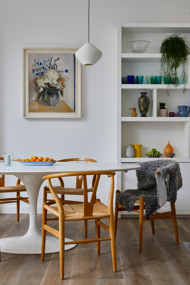 Cette photo montre une salle à manger ouverte sur le salon tendance avec un mur blanc et un sol en bois brun.