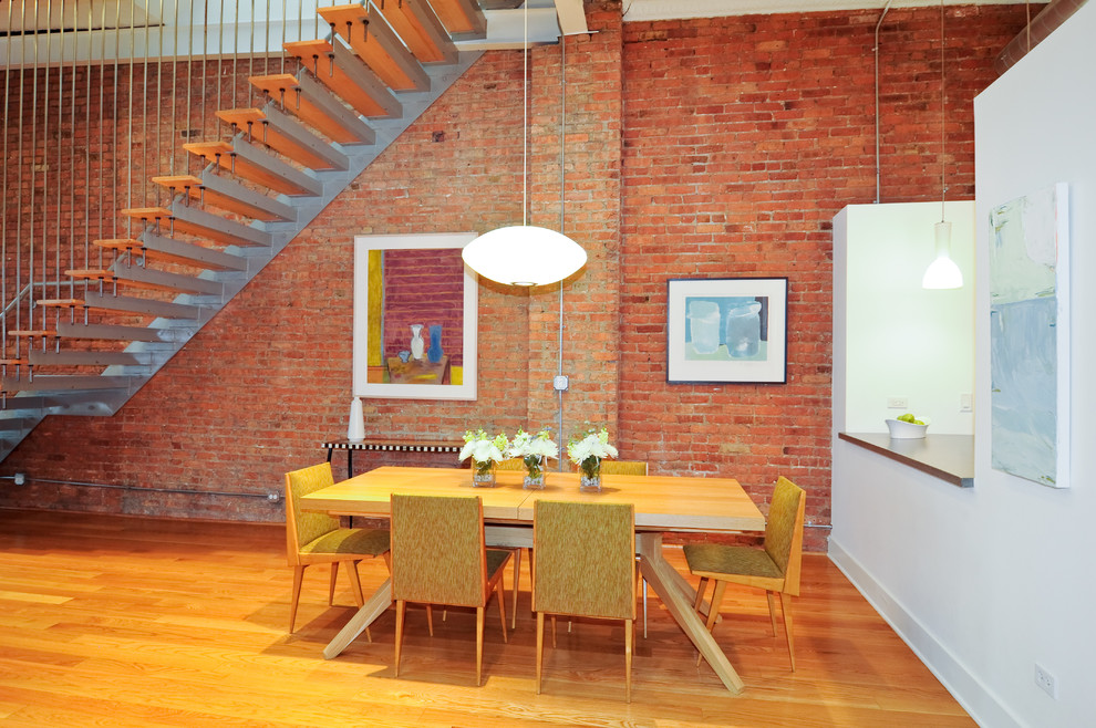 Immagine di una sala da pranzo aperta verso il soggiorno industriale con pareti rosse e pavimento in legno massello medio