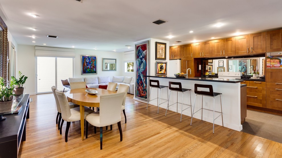 This is an example of a medium sized contemporary kitchen/dining room in Miami with white walls, light hardwood flooring and brown floors.