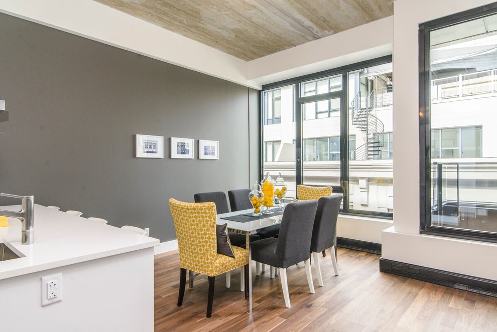 Immagine di una sala da pranzo aperta verso la cucina moderna di medie dimensioni con pareti grigie, pavimento in legno massello medio e nessun camino