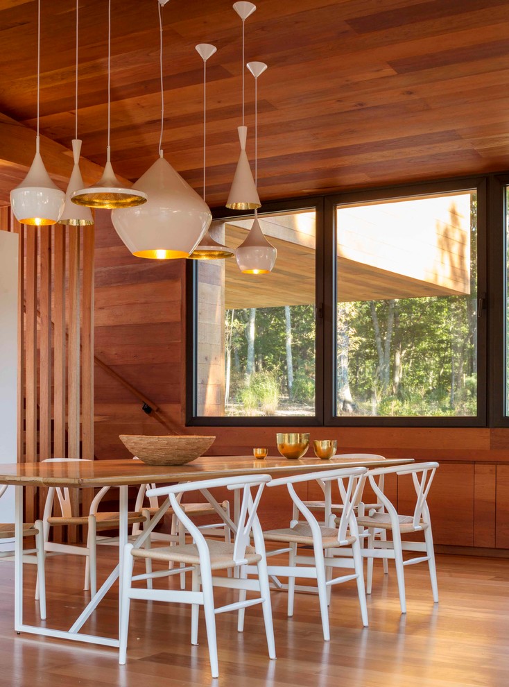 Aménagement d'une salle à manger ouverte sur le salon bord de mer avec un sol en bois brun.