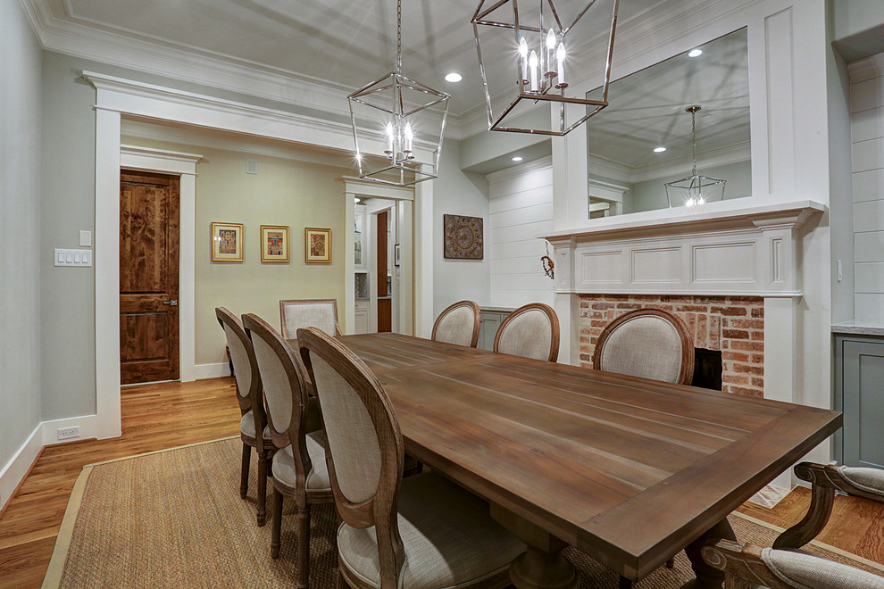 Inspiration pour une salle à manger traditionnelle fermée avec un mur gris, un sol en bois brun, une cheminée standard, un manteau de cheminée en brique et un sol marron.
