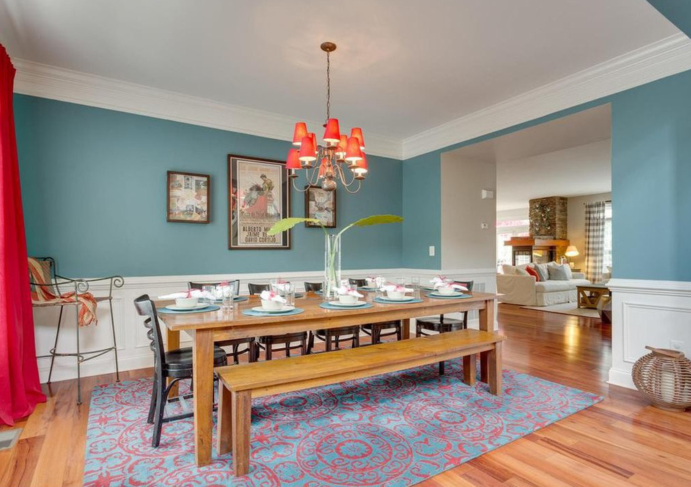 Exemple d'une salle à manger ouverte sur le salon chic de taille moyenne avec un mur bleu, un sol en bois brun et un sol marron.