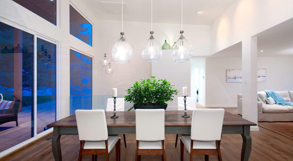 Idée de décoration pour une salle à manger ouverte sur le salon minimaliste de taille moyenne avec un mur blanc, un sol en bois brun, aucune cheminée et un sol marron.