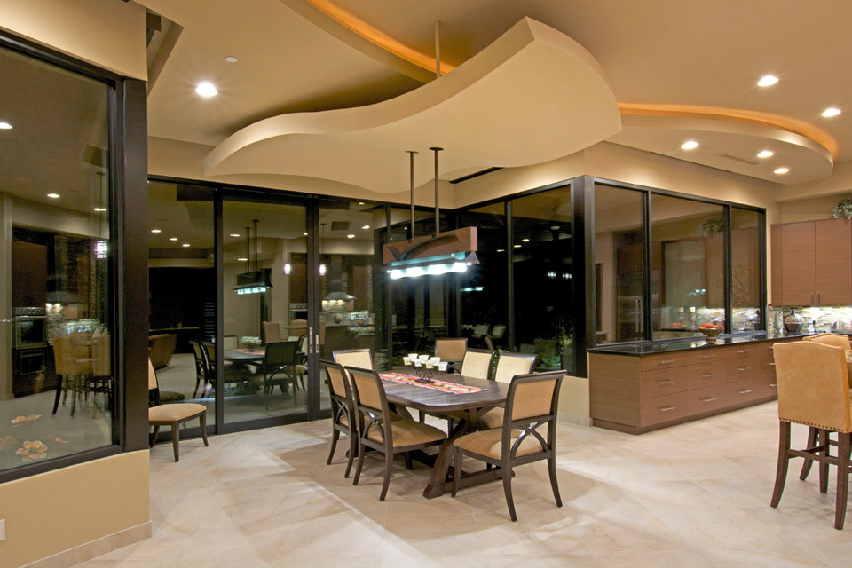 Aménagement d'une salle à manger ouverte sur le salon sud-ouest américain avec un mur beige et un sol en travertin.