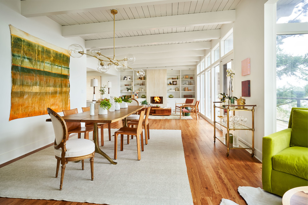 Immagine di una grande sala da pranzo aperta verso il soggiorno contemporanea con pareti bianche, pavimento in legno massello medio e pavimento marrone