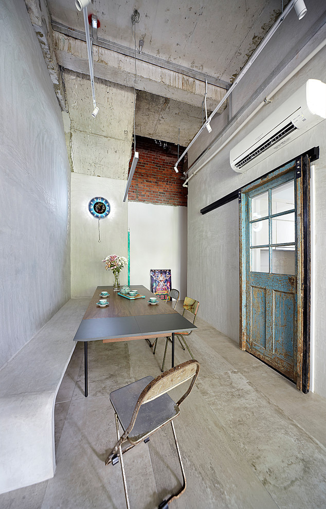 Réalisation d'une salle à manger urbaine fermée avec un mur gris et sol en béton ciré.