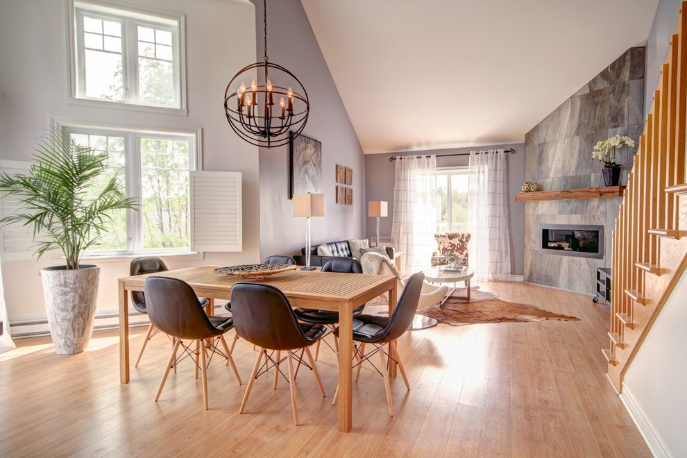 Esempio di una sala da pranzo aperta verso la cucina scandinava di medie dimensioni con pareti grigie, parquet chiaro e cornice del camino piastrellata