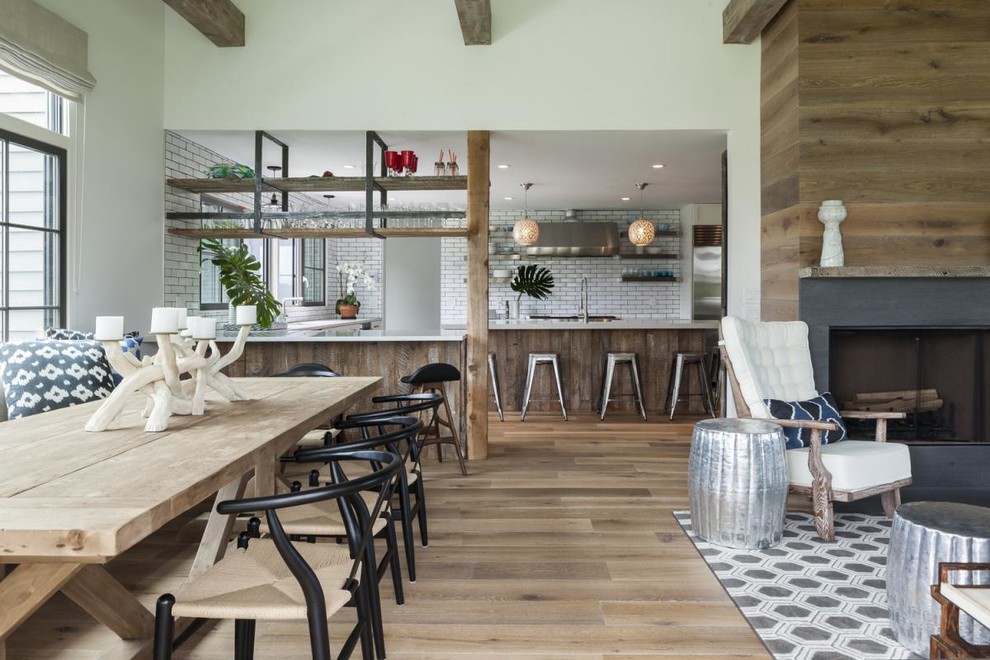 Inspiration pour une salle à manger ouverte sur le salon design avec un mur blanc, un sol en bois brun, un manteau de cheminée en pierre et une cheminée standard.