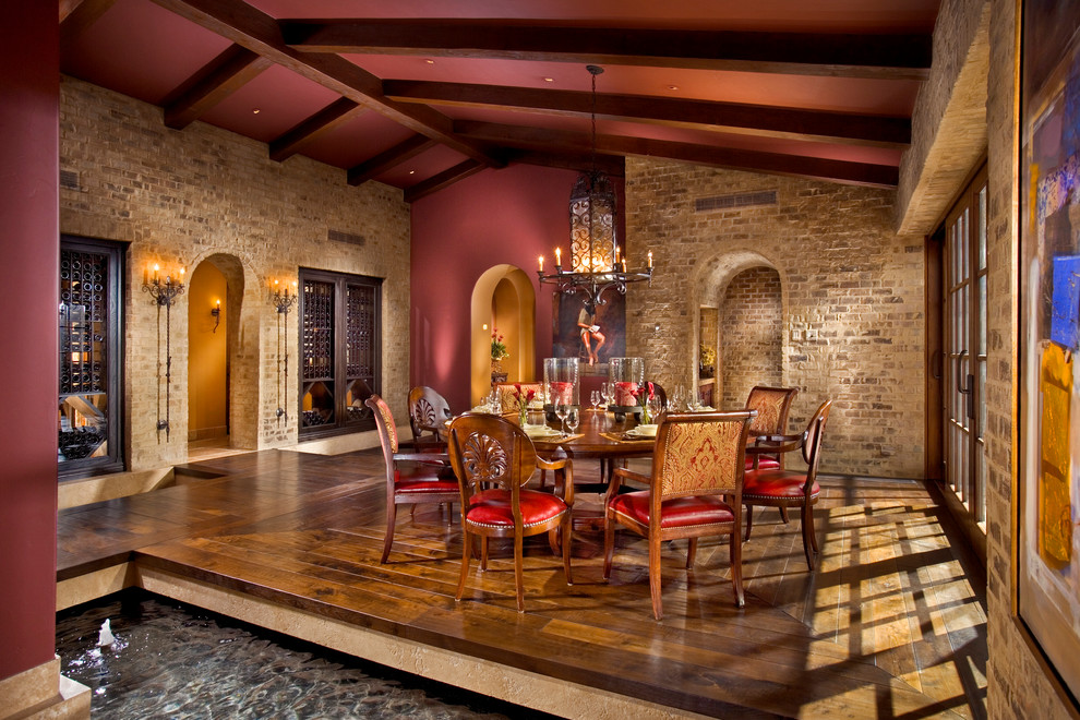Mediterranean dining room in Orange County with red walls, medium hardwood flooring and brown floors.