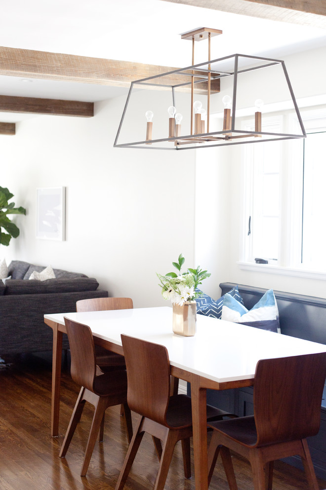 Cette photo montre une salle à manger ouverte sur la cuisine chic de taille moyenne avec parquet foncé, un sol marron et un mur blanc.