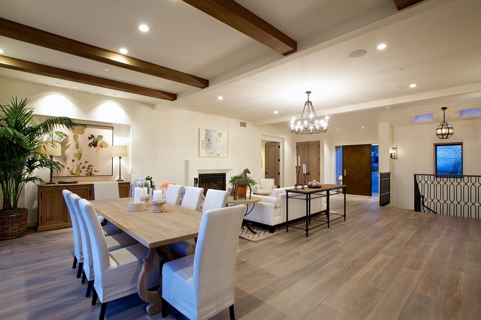 Exemple d'une grande salle à manger ouverte sur le salon tendance avec un mur blanc, parquet foncé, une cheminée standard, un manteau de cheminée en plâtre, un sol marron et éclairage.