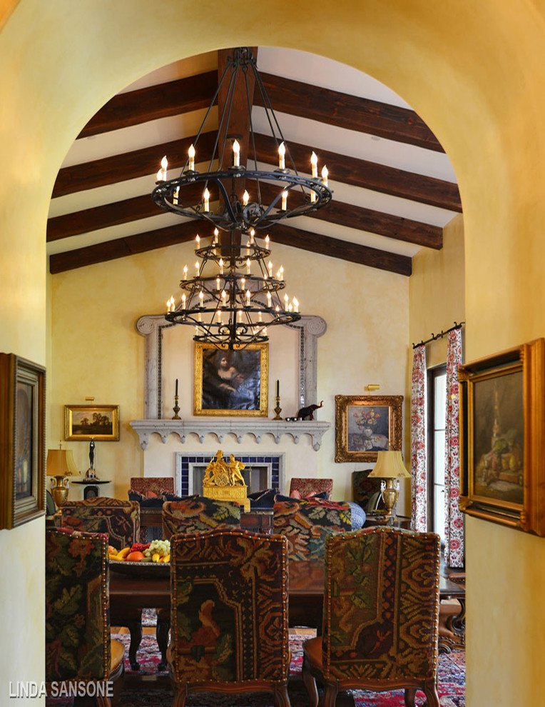 Cette image montre une salle à manger ouverte sur la cuisine méditerranéenne de taille moyenne avec un mur beige et un manteau de cheminée en pierre.