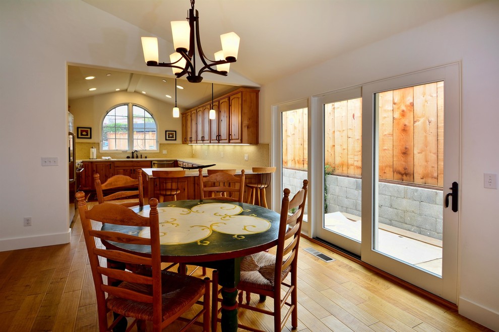 Immagine di una sala da pranzo aperta verso la cucina american style con pareti bianche e parquet chiaro