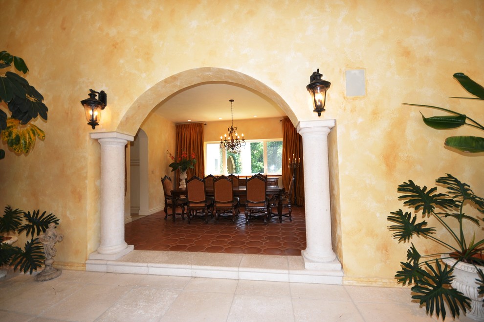 Idée de décoration pour une grande salle à manger méditerranéenne fermée avec un mur jaune et tomettes au sol.