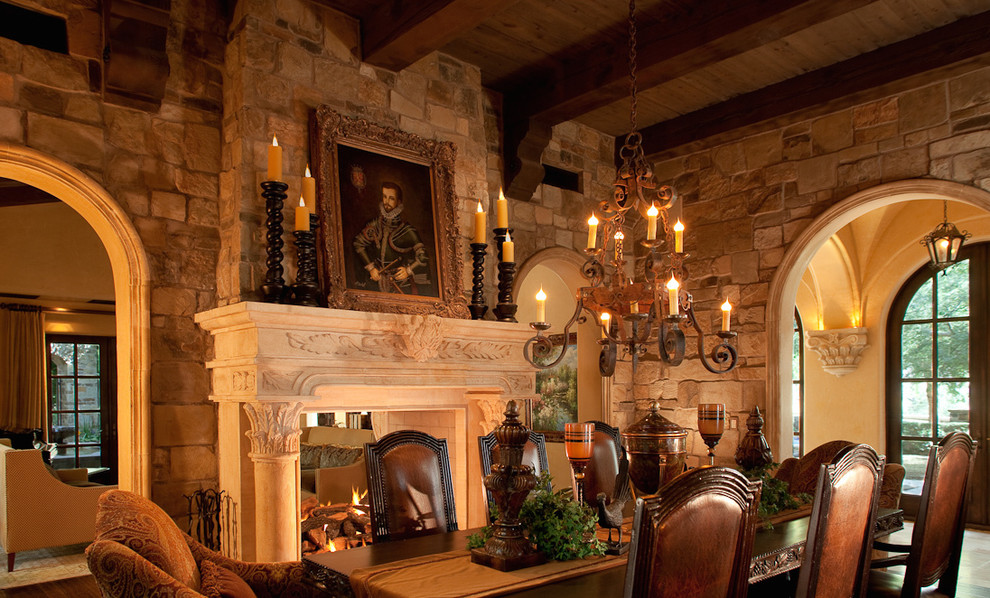 На фото: огромная отдельная столовая в стиле рустика с коричневыми стенами, полом из травертина, двусторонним камином и фасадом камина из камня с