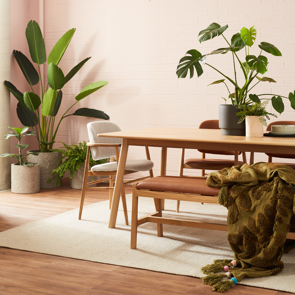Cette photo montre une salle à manger ouverte sur le salon tendance de taille moyenne avec un mur rose, un sol en vinyl et un sol marron.