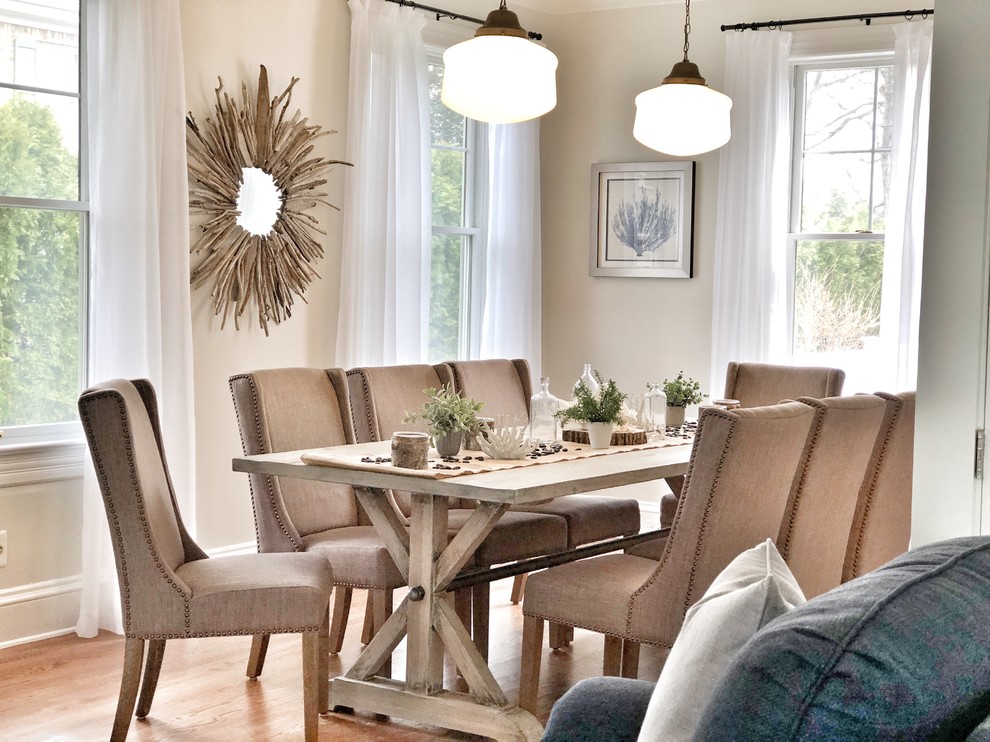 This is an example of a large beach style dining room in Other with white walls, medium hardwood flooring, a standard fireplace, a brick fireplace surround and brown floors.