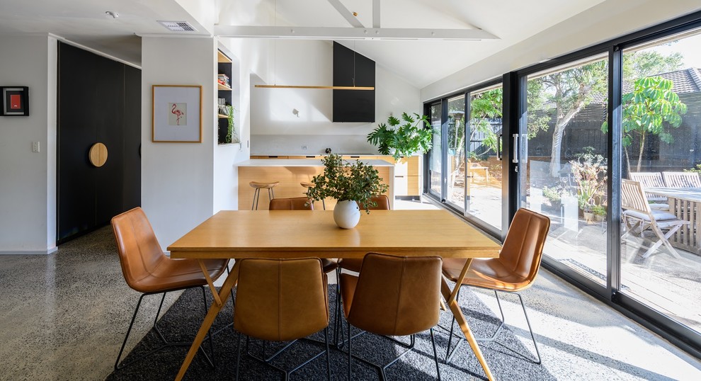Esempio di una sala da pranzo aperta verso il soggiorno moderna di medie dimensioni con pareti bianche, pavimento in cemento e pavimento grigio
