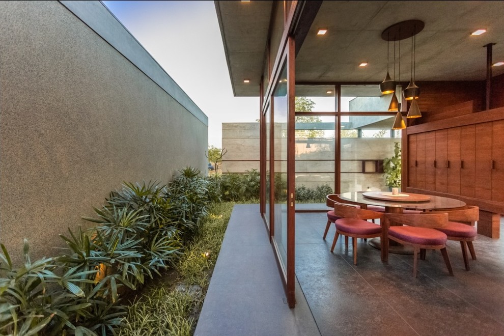 Esempio di una sala da pranzo aperta verso il soggiorno tropicale con pavimento in cemento e pavimento grigio