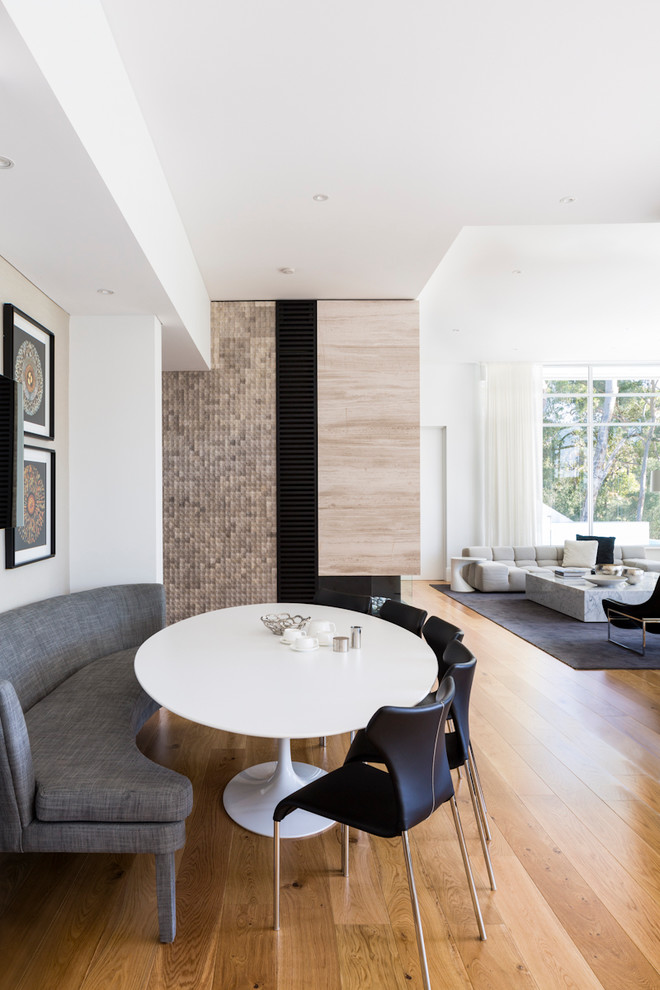 Foto di una sala da pranzo aperta verso il soggiorno minimal con pareti bianche e pavimento in legno massello medio