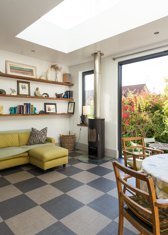 Стильный дизайн: маленькая гостиная-столовая в современном стиле с серыми стенами, полом из ламината, печью-буржуйкой и серым полом для на участке и в саду - последний тренд