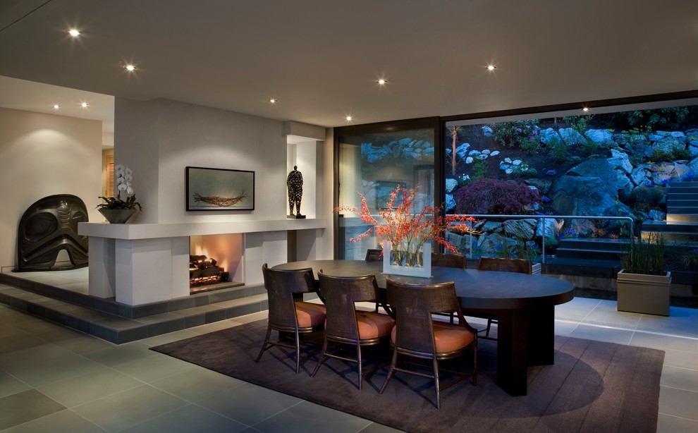 This is an example of a contemporary dining room in Vancouver with a two-sided fireplace.
