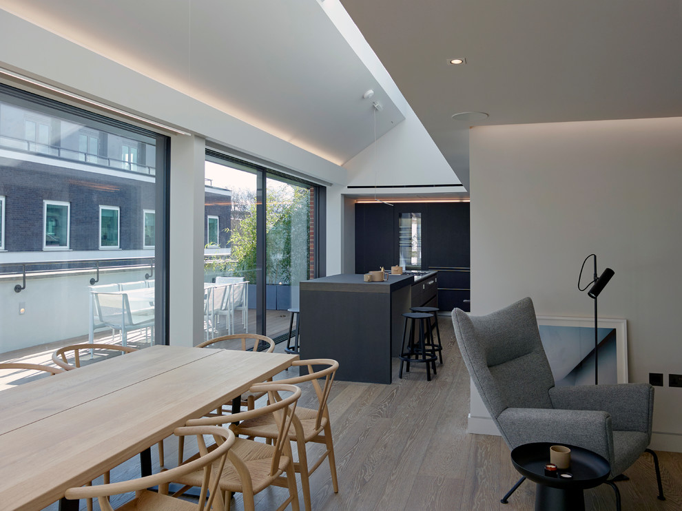 Foto di una grande sala da pranzo aperta verso il soggiorno contemporanea con pareti grigie e parquet chiaro