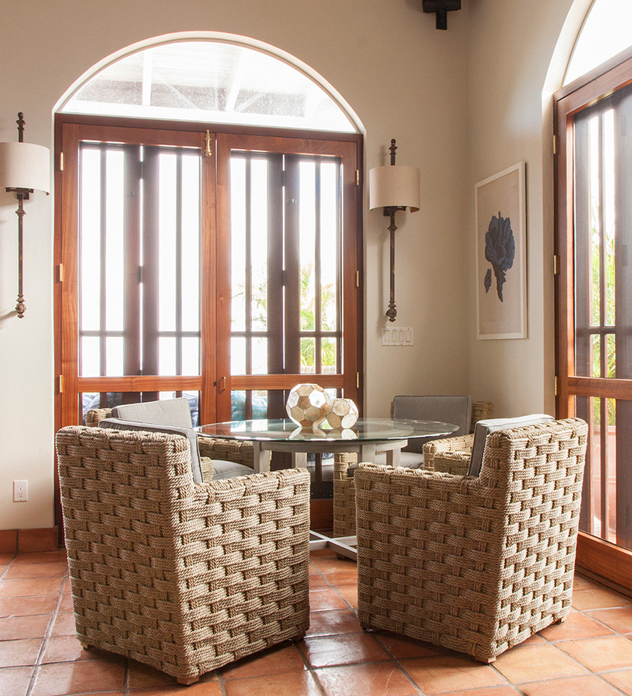 Immagine di una piccola sala da pranzo aperta verso il soggiorno tropicale con pavimento in terracotta, pareti bianche, soffitto a volta e pavimento arancione