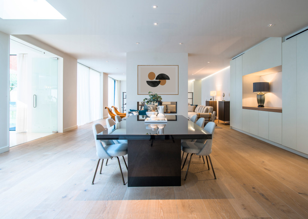 Design ideas for a contemporary dining room in London with white walls, medium hardwood flooring and brown floors.