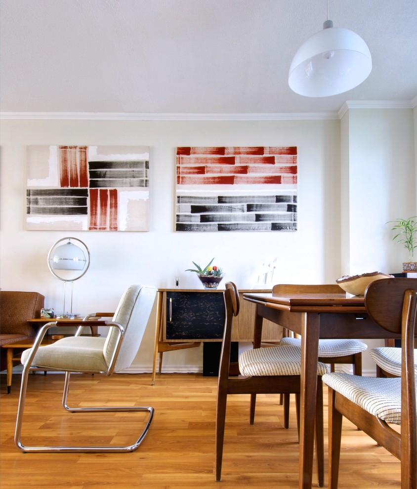 This is an example of a midcentury dining room in Toronto with white walls and medium hardwood flooring.