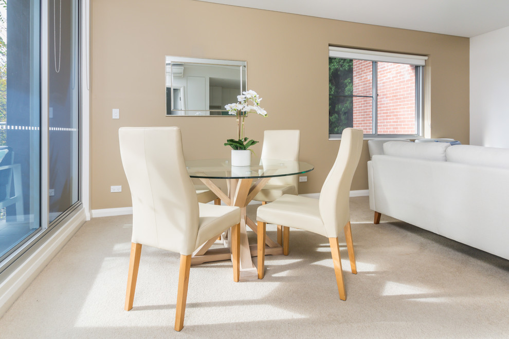 Foto di una piccola sala da pranzo aperta verso il soggiorno minimal con pareti beige, moquette, nessun camino e pavimento beige