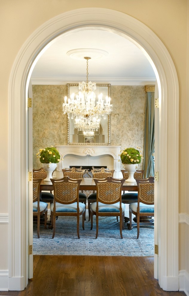 Immagine di una sala da pranzo classica chiusa con pareti gialle, pavimento in legno massello medio e camino classico