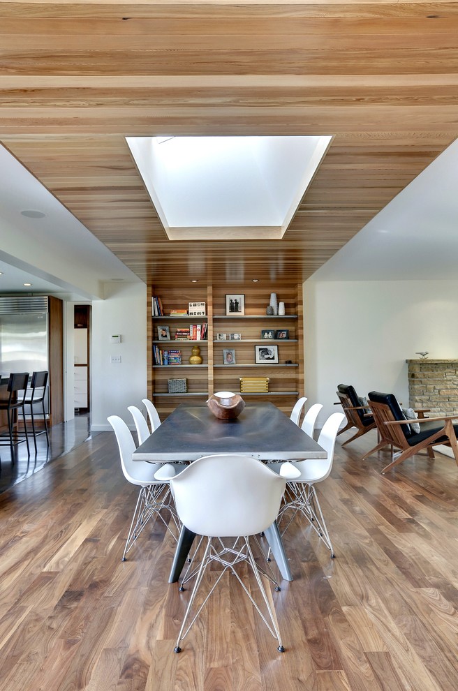 Diseño de comedor contemporáneo abierto con paredes blancas y suelo de madera en tonos medios
