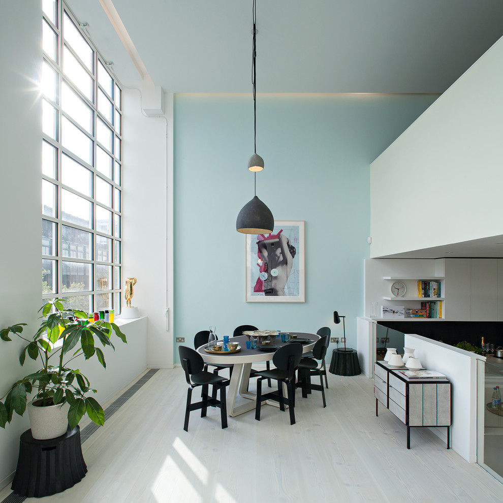 Diseño de comedor nórdico abierto con paredes azules y suelo de madera clara