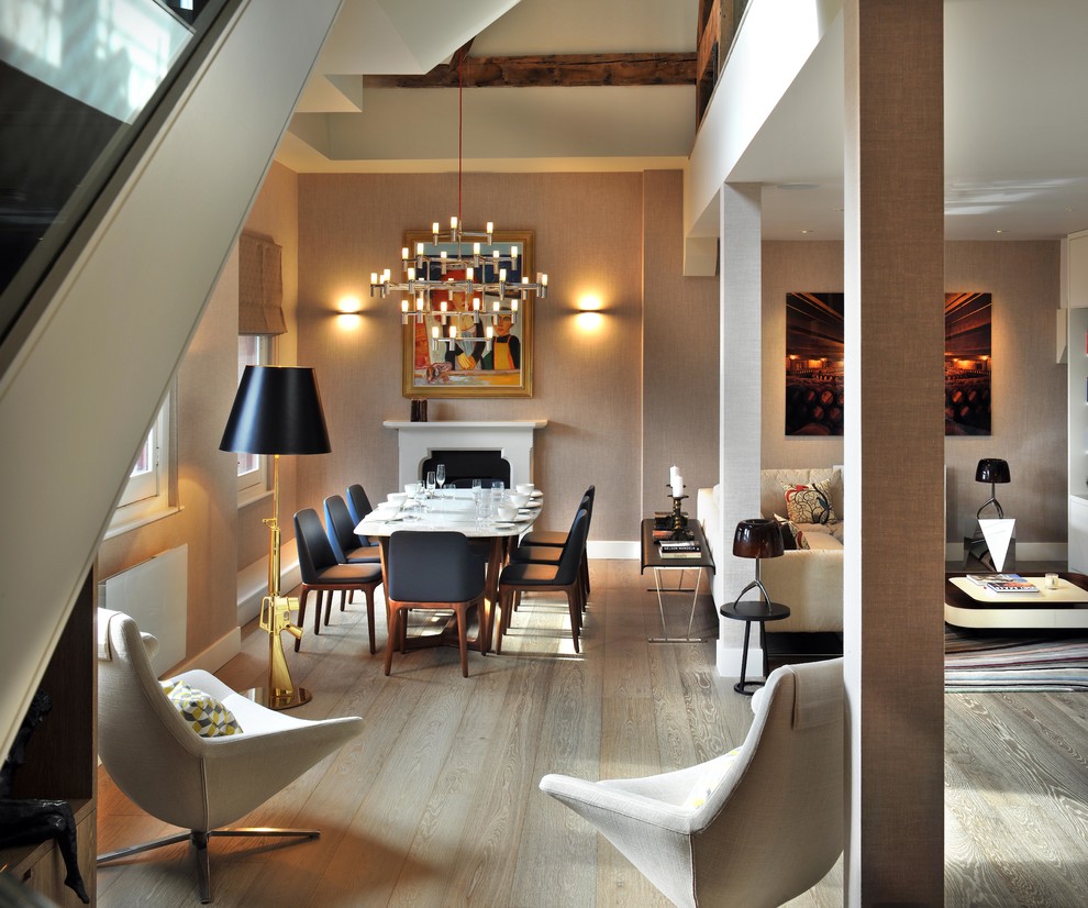 Ispirazione per una sala da pranzo aperta verso il soggiorno minimal di medie dimensioni con pareti beige, camino classico e parquet chiaro