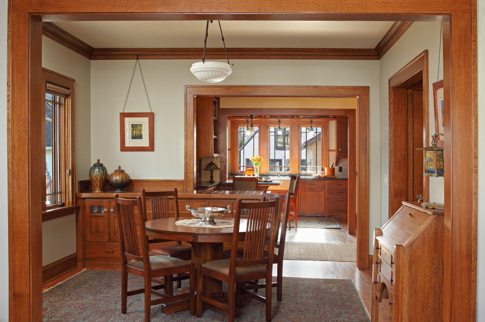 Aménagement d'une salle à manger craftsman avec un mur blanc, un sol en bois brun et aucune cheminée.