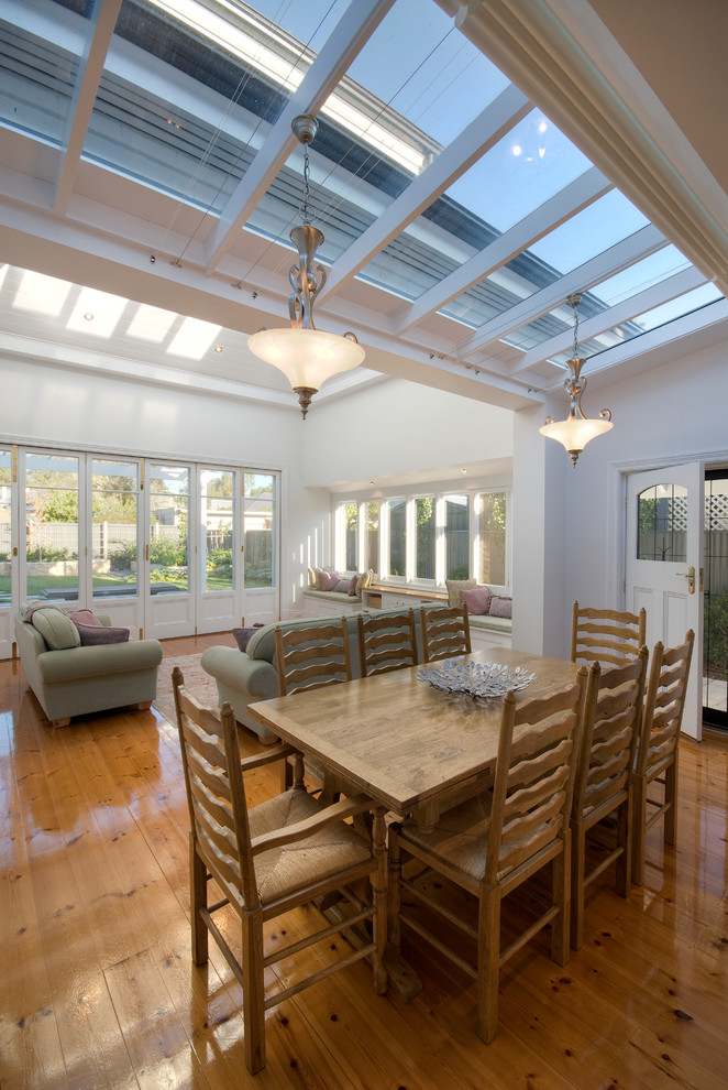 Immagine di una sala da pranzo aperta verso la cucina tradizionale con pareti bianche e pavimento in legno massello medio
