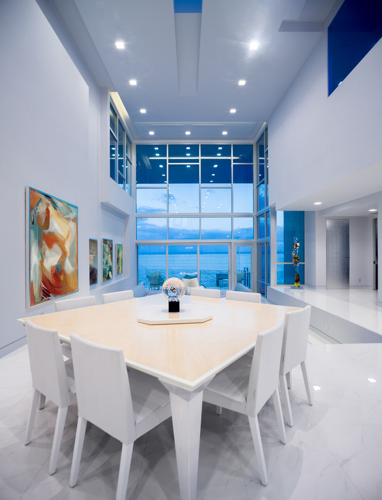 Cette photo montre une salle à manger ouverte sur le salon tendance de taille moyenne avec un mur blanc et un sol blanc.