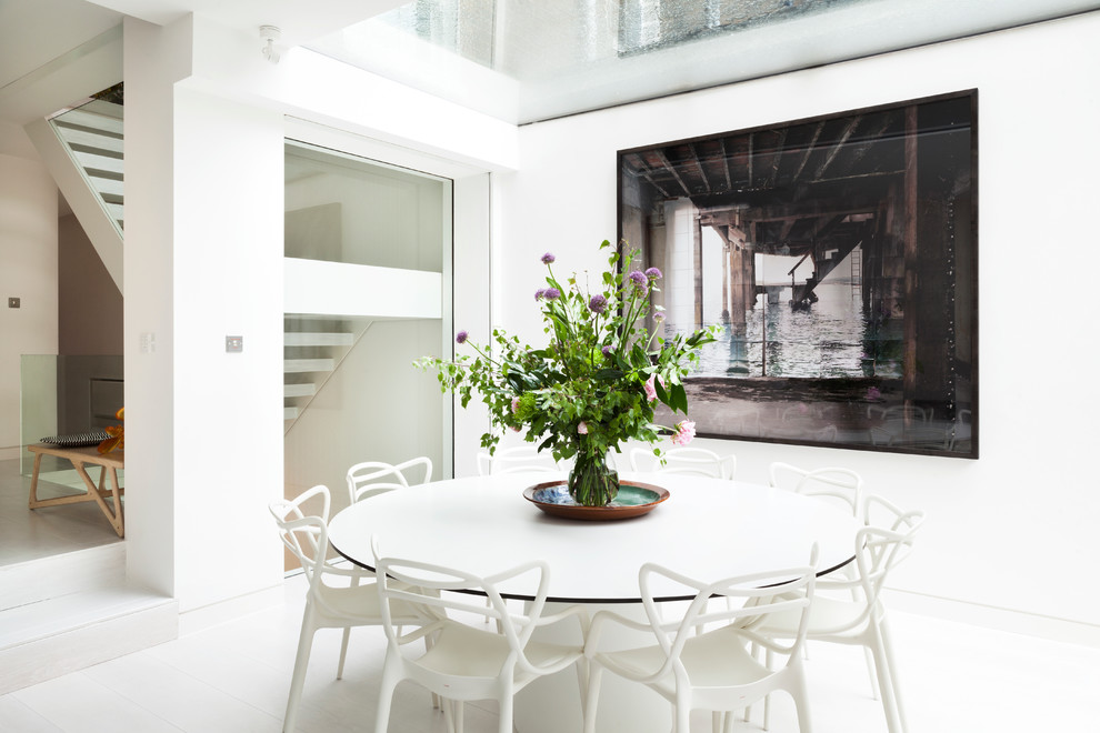 Large contemporary open plan dining room in London with white walls, light hardwood flooring and no fireplace.