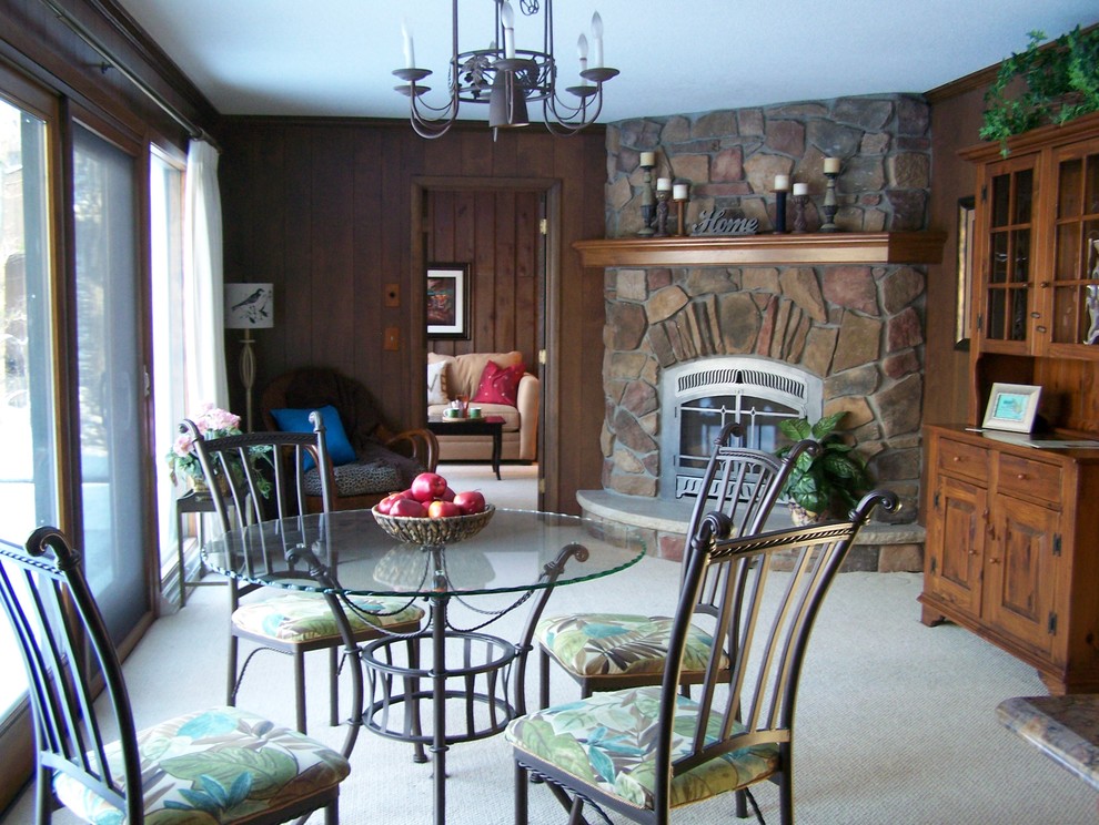 This is an example of a small traditional kitchen/dining room in Minneapolis with brown walls, carpet, a corner fireplace and a stone fireplace surround.