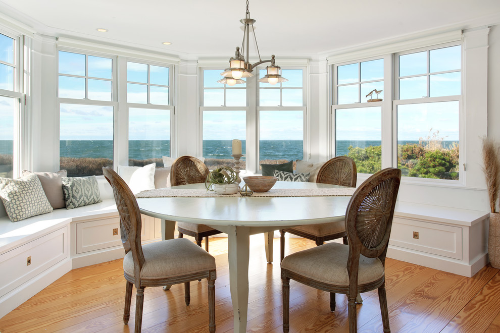 Nautical dining room in Boston with white walls, light hardwood flooring and no fireplace.
