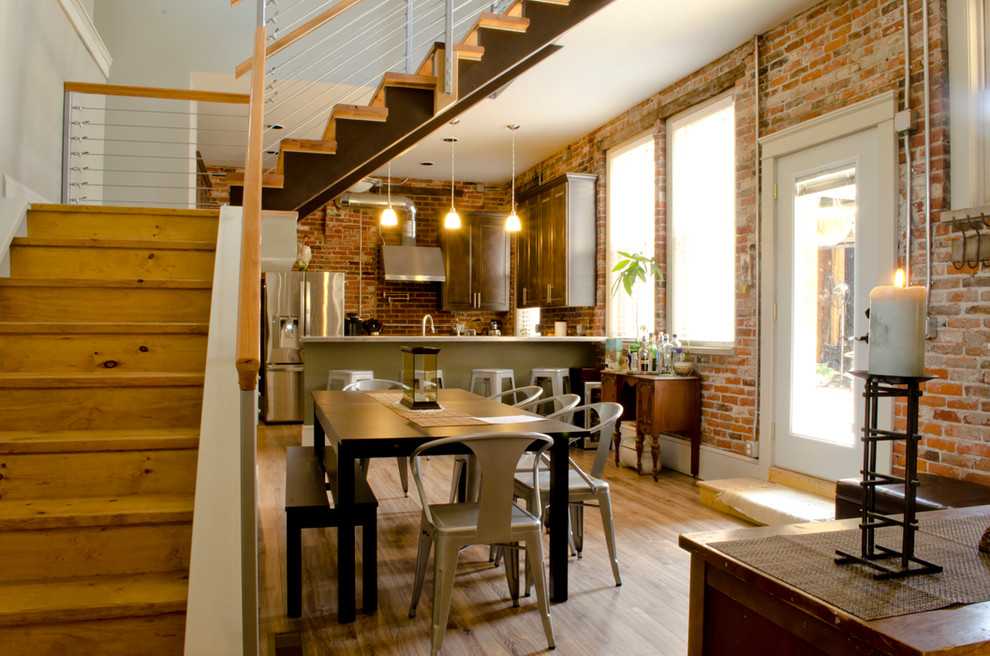 Foto di una sala da pranzo aperta verso la cucina industriale con pavimento in legno massello medio