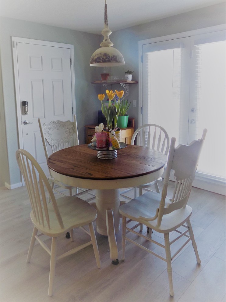 Idée de décoration pour une petite salle à manger ouverte sur le salon champêtre avec un mur bleu, sol en stratifié et un sol marron.